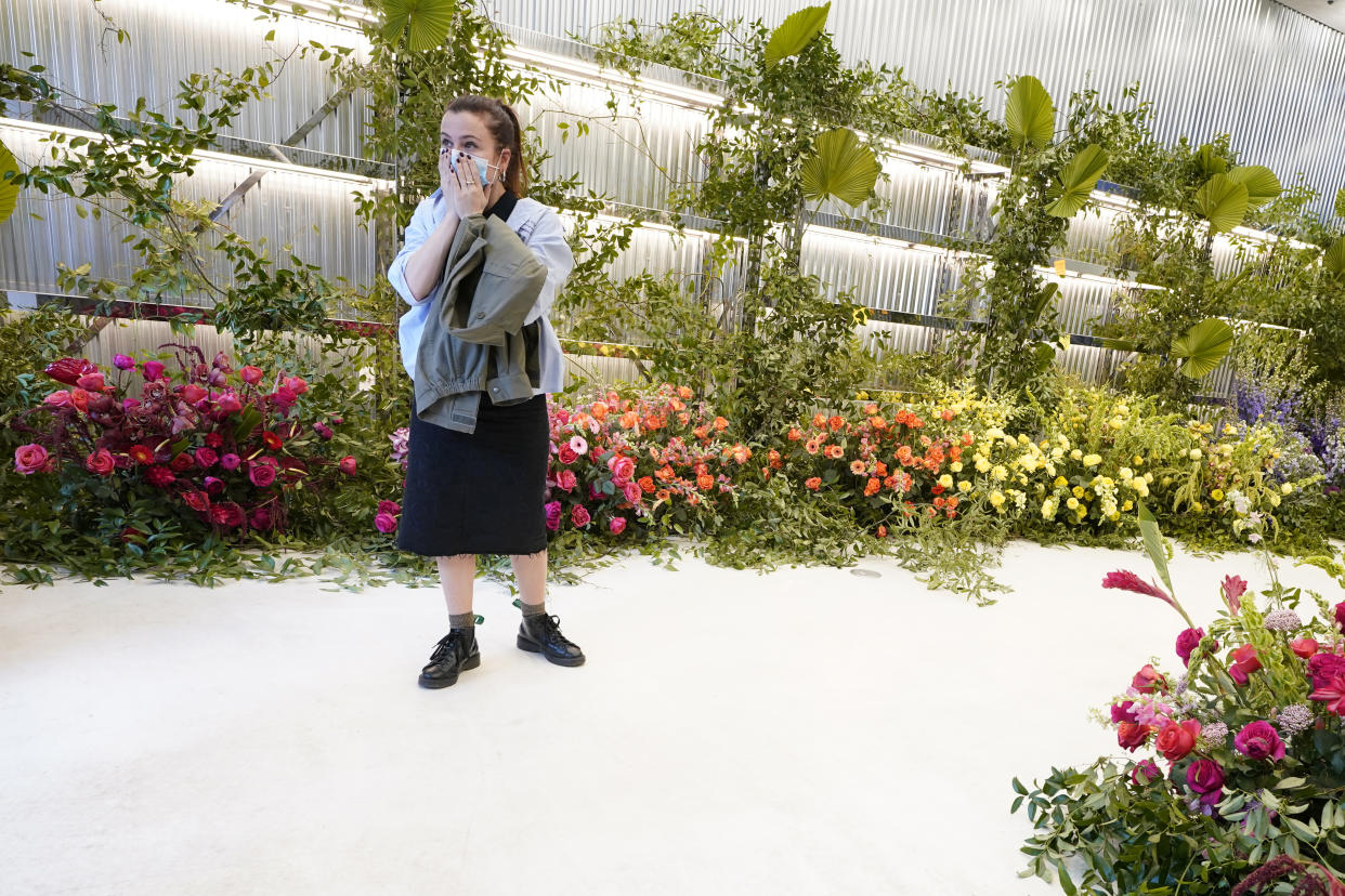 A shopper at the Off-White Label store, is overcome by the flowers left in memory of Virgil Abloh, the artistic director for Louis Vuitton's menswear, Tuesday, Nov. 30, 2021, in Miami. Louis Vuitton acquired Abloh's Off-White Label earlier this year. (AP Photo/Marta Lavandier)