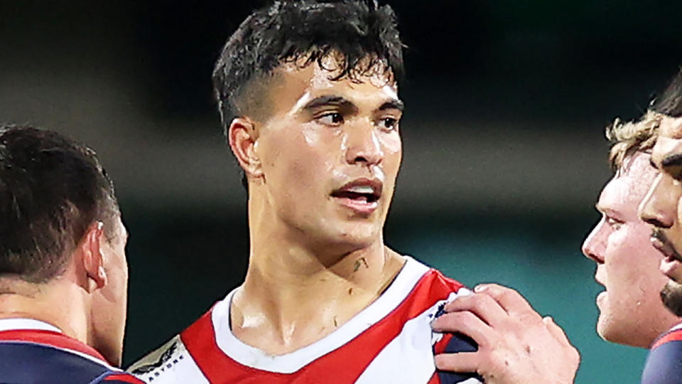 Joseph Suaalii confers with Sydney Roosters teammates during an NRL match.