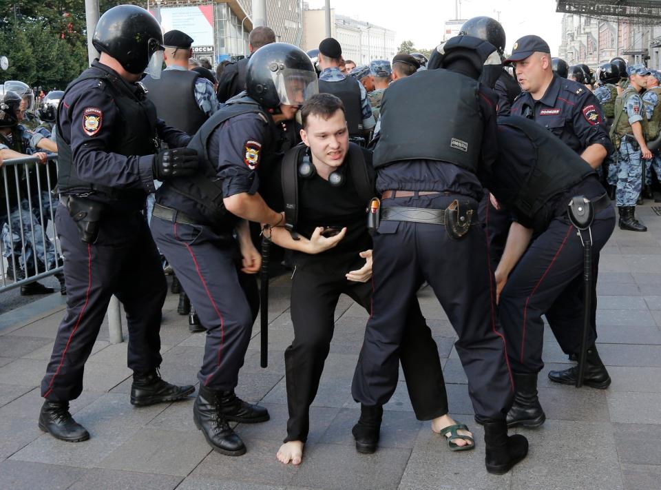 Police officers detain a man during an unsanctioned rally in the center of Moscow on July 27, 2019. Russian police are wrestling with demonstrators and have arrested hundreds in central Moscow during a protest demanding that opposition candidates be allowed to run for the Moscow city council.