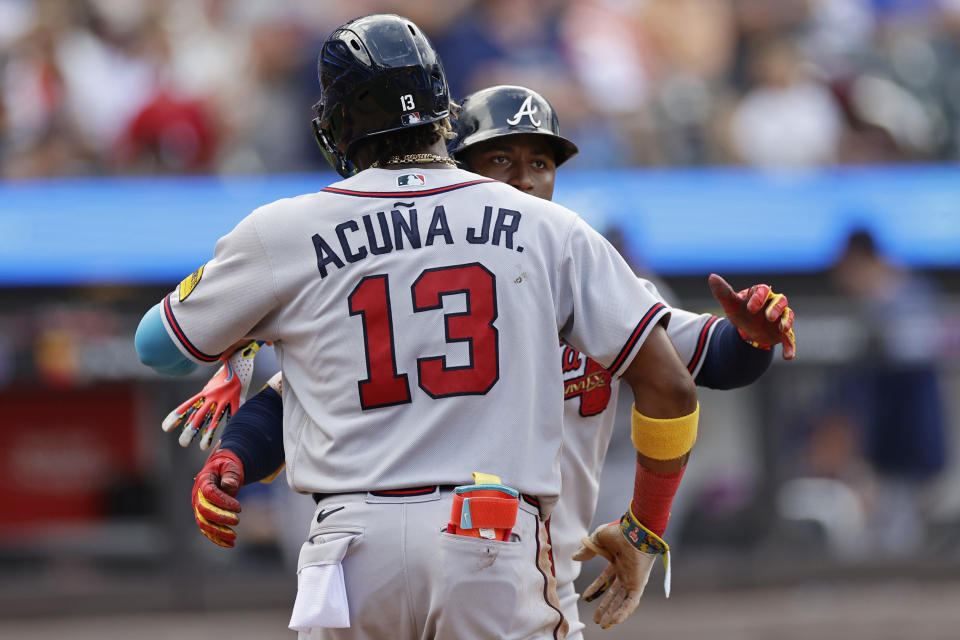 Atlanta Braves' Ozzie Albies is hugged after hitting a two-run home run by Ronald Acuna Jr. (13) against the New York Mets during the seventh inning in the first baseball game of a doubleheader on Saturday, Aug. 12, 2023, in New York. (AP Photo/Adam Hunger)