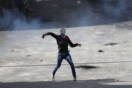 A Palestinian protester hurls stones towards Israeli troops during clashes at a protest against the Israeli offensive in Gaza, in the West Bank City of Hebron August 9, 2014. REUTERS/Ammar Awad