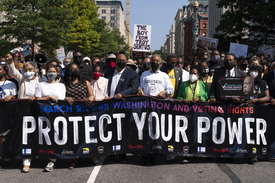 The Rev. Al Sharpton, third from right in front, holds a banner with Martin Luther King, III, Rep. Sheila Jackson Lee, D-Texas, second from right, and Rep. Al Green, D-Texas, right, among others, during the march to call for sweeping protections against a further erosion of the Voting Rights Act of 1965, Saturday, Aug. 28, 2021, in Washington. (AP Photo/Jose Luis Magana)