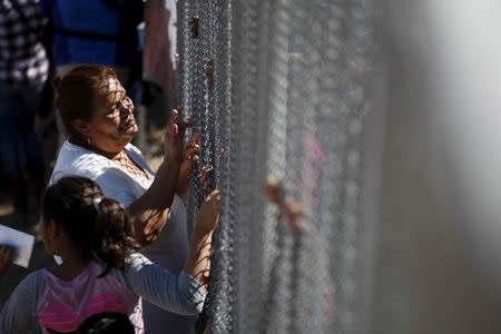 FILE PHOTO: A woman touches a family member through the border fence between Ciudad Juarez and El Paso, United States, after a bi-national Mass in support of migrants in Ciudad Juarez, Mexico, February 15, 2016. REUTERS/Jose Luis Gonzalez