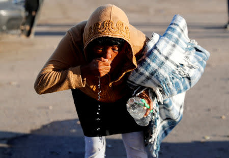 A migrant woman, part of a caravan of thousands traveling from Central America en route to the United States, washes her mouth with water from a plastic bottle at a makeshift camp at a gas station where the migrants wait for buses in Navojoa, Mexico November 16, 2018. REUTERS/Kim Kyung-Hoon