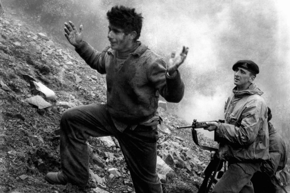 With hands raised, Agustinds Efstathios, 22, climbs the mountainside from his EOKA hideout on March 3, 1957, under the gun of a British soldier of the Duke of Wellington regiment after he surrendered with three others when the cave they were hiding in was surrounded by British troops. A fifth man, Gregoris Pieri Afxentios, second-in-command to EOKA leader Georgios Grivas, refused to surrender and fought until he was killed by a blast in the cave hidden in a deep valley of the Trodos mountains of Cyprus, a mile from the Isolated monastery of Macheras. (AP Photo, File)