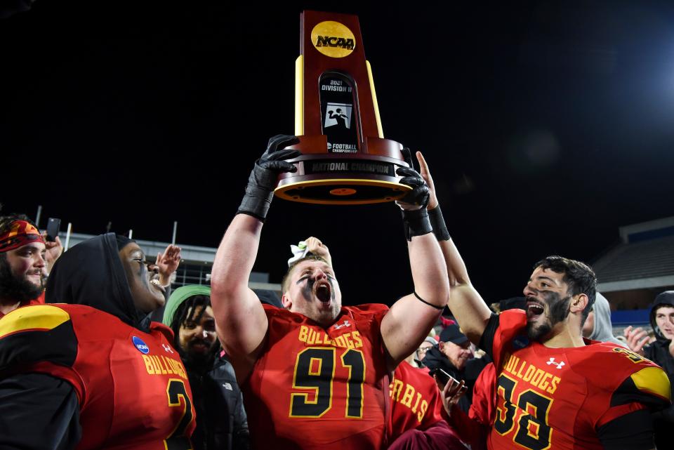 From left, Ferris State defensive lineman Jordan Jones (2), smiles as defensive tackle Austin Simpson (91) hoists the NCAA Division II college football championship trophy next to linebacker Mohamed Amen (38), after defeating Valdosta State by a final of 58-17 in McKinney, Texas, Saturday, Dec. 18, 2021. (AP Photo/Emil Lippe)