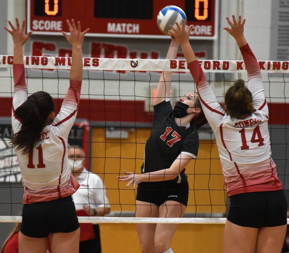 Hannah Fausze of Bedford goes up to spike with Sydney Button and Kamryn Bice of Monroe attempting to block last season.