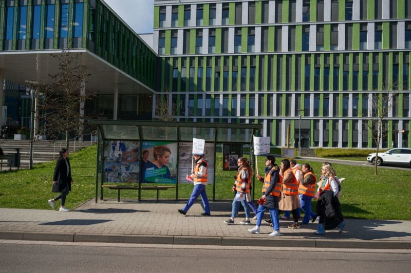 Doctors at Saarland University Hospital walk across the hospital grounds during a strike aim to increase the pressure on the Collective Bargaining Association of German States in the wage negotiations. Oliver Dietze/dpa