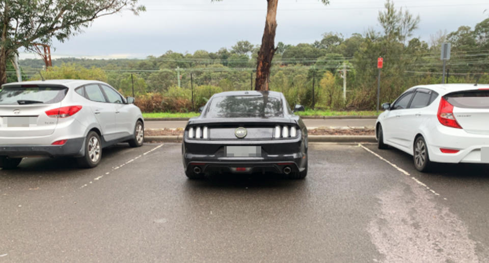 The black Ford Mustang parked in between two parking bays in Springwood. 