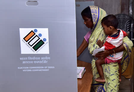 A woman holds a child as she casts her vote at a polling station during the second phase of general election in Hojai district in the northeastern state of Assam, India, April 18, 2019. REUTERS/Anuwar Hazarika