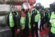 A female police officer covered in red paint stands by during a women's protest against the latest murder of two women, in Mexico City, Saturday, Jan. 25, 2020. During the past couple of weeks two women activists, attorney Yunuen Lopez Sanchez and Isabel Cabanillas de la Torre where murdered by unknown assailants. (AP Photo/Ginnette Riquelme)