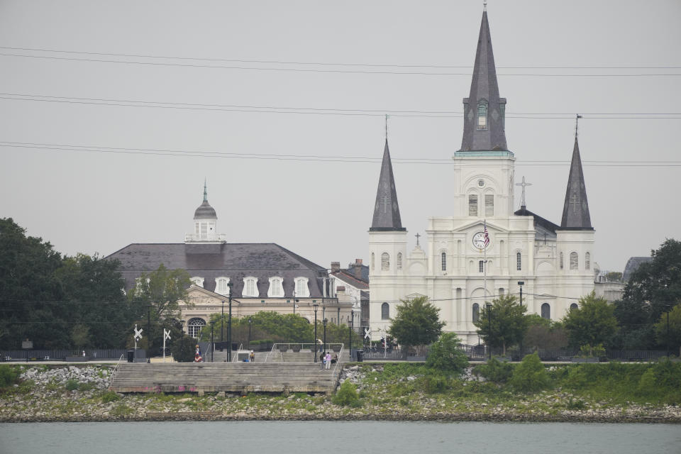 The low water level of the Mississippi River is seen as people sit on steps that normally meet the river near St. Louis Cathedral in the French Quarter of New Orleans, Monday, Sept. 25, 2023. (AP Photo/Gerald Herbert)