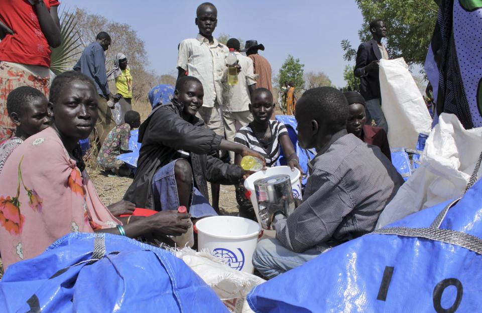 In this photo taken Tuesday, April 1, 2014, a South Sudanese family distributes cooking oil received from the World Food Programme (WFP) via air drop in Nyal, Unity State, South Sudan. Desperate South Sudan villagers, fleeing fighting across the country, are eating grass and roots to survive as WFP starts costly air drops of food, three times more expensive than road deliveries, to northern parts of the country, straining the ramped-up humanitarian response because only a third of the U.N.'s requested $1.27 billion has been raised for the crisis. (AP Photo/Ilya Gridneff)