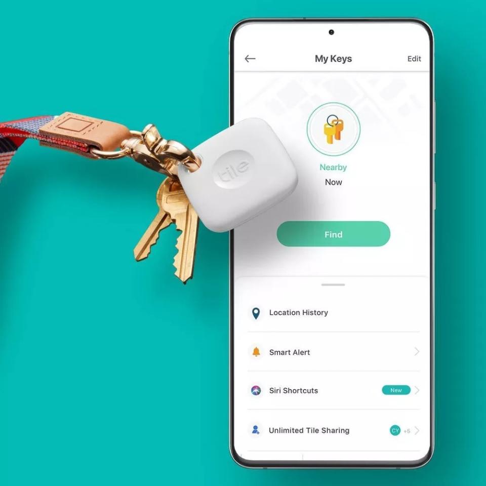 The Tile tag on a set of keys next to a phone displaying the tag's app on its screen