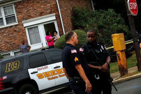 Onlookers watch while law enforcement officers stand guard near the site where Ahmad Khan Rahami, sought in connection with a bombing in New York, was taken into custody in Linden, New Jersey, U.S., September 19, 2016. REUTERS/Eduardo Munoz