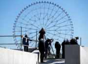 Media members report as a Ferris wheel is a background at the construction site of the Kasai Canoe Slalom Centre for Tokyo 2020 Olympic games in Tokyo, Japan February 12, 2019. REUTERS/Issei Kato