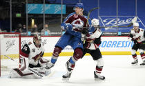 Colorado Avalanche left wing Andre Burakovsky, center, jumps as the puck sails into Arizona Coyotes goaltender Darcy Kuemper and Coyotes defenseman Jason Demers fights for position in front of the net in the first period of an NHL hockey game Monday, March 8, 2021, in downtown Denver. (AP Photo/David Zalubowski)