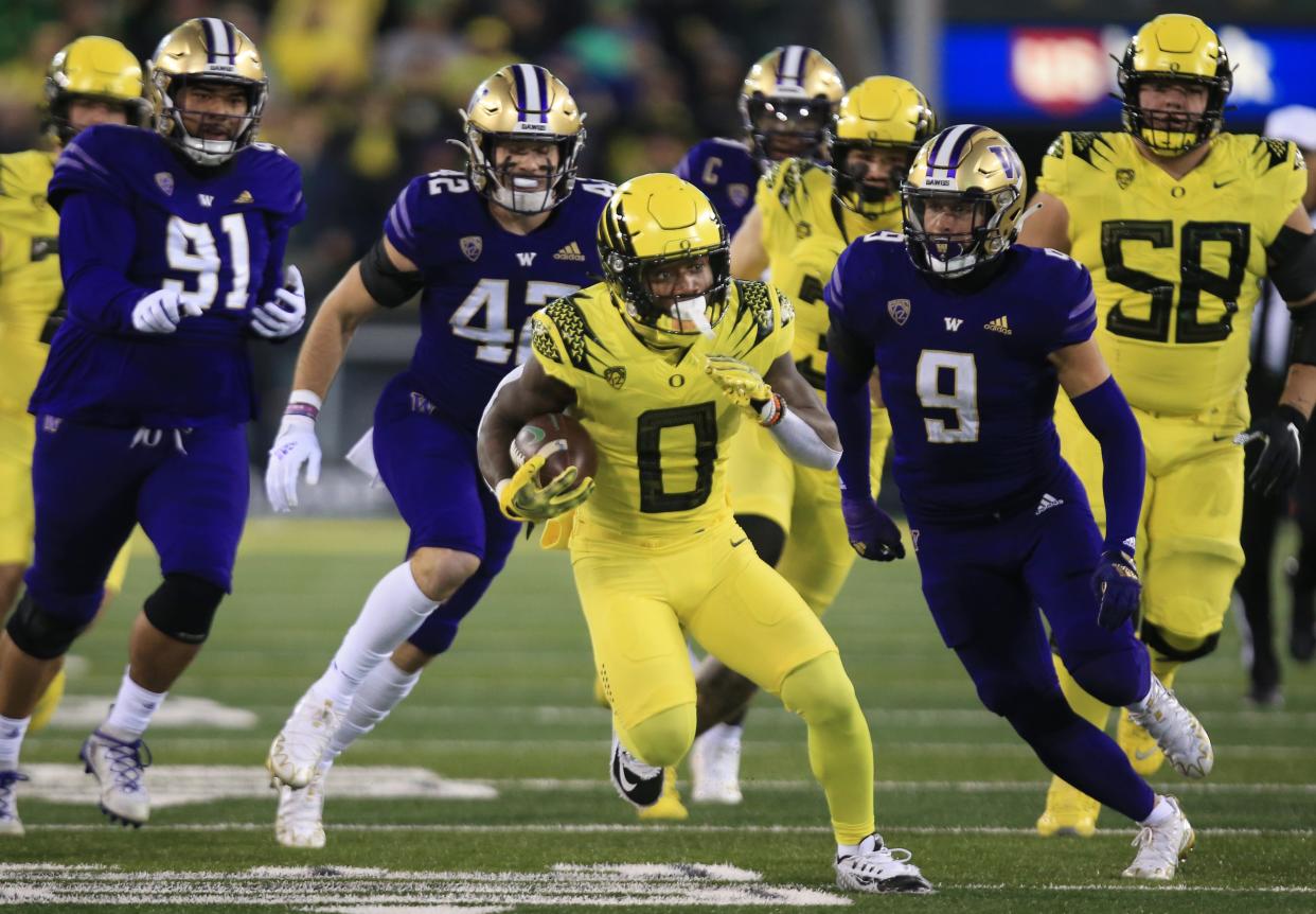 Oregon's Bucky Irving, center, breaks through the Washington defense during the second quarter Saturday, Nov. 12, 2022, at Autzen Stadium in Eugene, Ore.