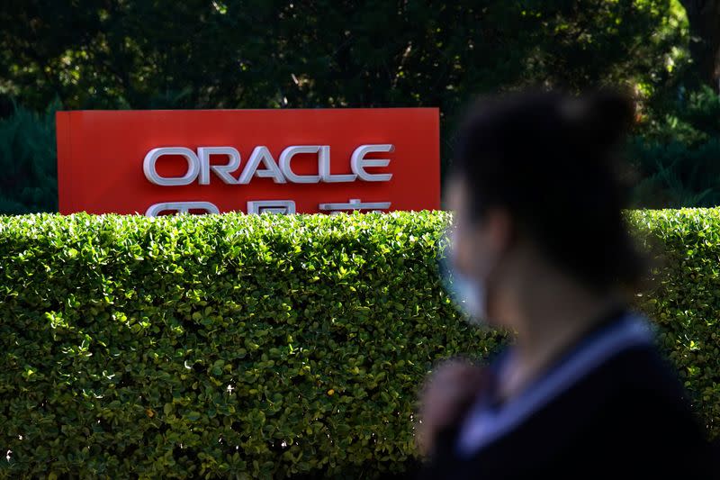 Pedestrian wearing face mask following the COVID-19 outbreak walks past a sign of Oracle in front of its office buildings in Beijing