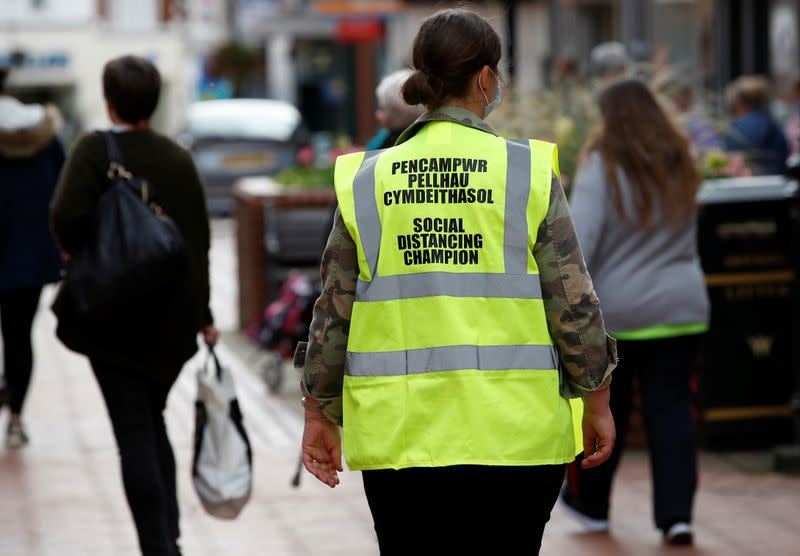 A council worker wearing a safety vest marked 'social distancing champion' walks through the town centre following the outbreak of the coronavirus disease (COVID-19) in Wrexham, Britain