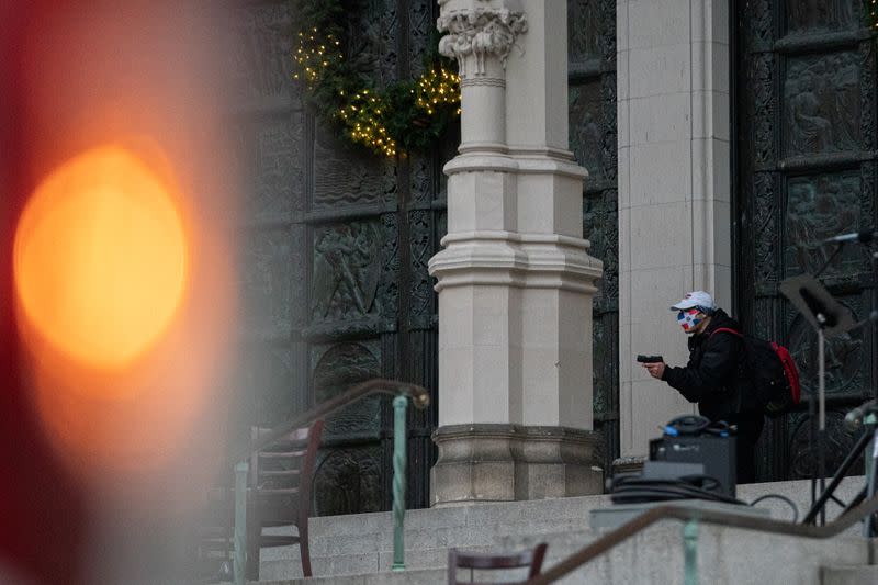 A man wearing a protective mask points his guns outside the Cathedral Church of St. John the Divine in the Manhattan borough of New York City