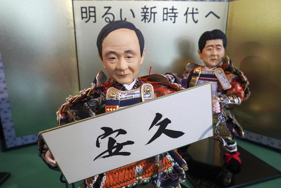 In this Thursday, March 28, 2019, photo, Japanese traditional dolls depicting Japanese Chief Cabinet Secretary Yoshihide Suga holding the new era name "Ankyu," speculated by about 180 general public, displayed with a doll depicting Japanese Prime Minister Shinzo Abe, right, at Kyugetsu, a Japanese traditional doll company, in Tokyo. What’s in a name? Quite a lot if you’re a Japanese citizen awaiting the official announcement Monday, April 1, 2019 of what the soon-to-be-installed new emperor’s next era will be called. It’s a proclamation that has happened only twice in nearly a century, and the new name will follow Emperor Naruhito, after his May 1 investiture, for the duration of his rule, attaching itself to much of what happens in Japan. (AP Photo/Eugene Hoshiko)