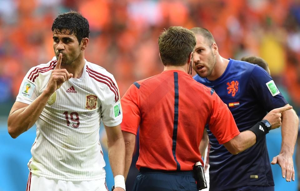 Diego Costa, jugando con la selección española, manda callar a alguien llevándose la mano a la boca mientras el árbitro discute con un jugador de Países Bajos.