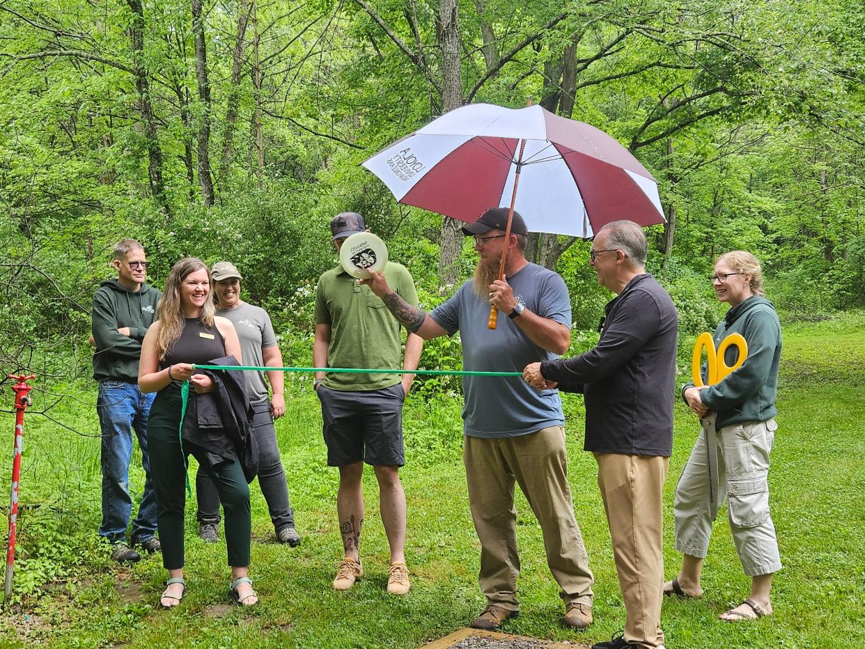 Members of the Ross County Park District cut the ribbon, with a disc, to officially open the new disc golf course at the Metahqua Nature Preserve on May 17, 2024.