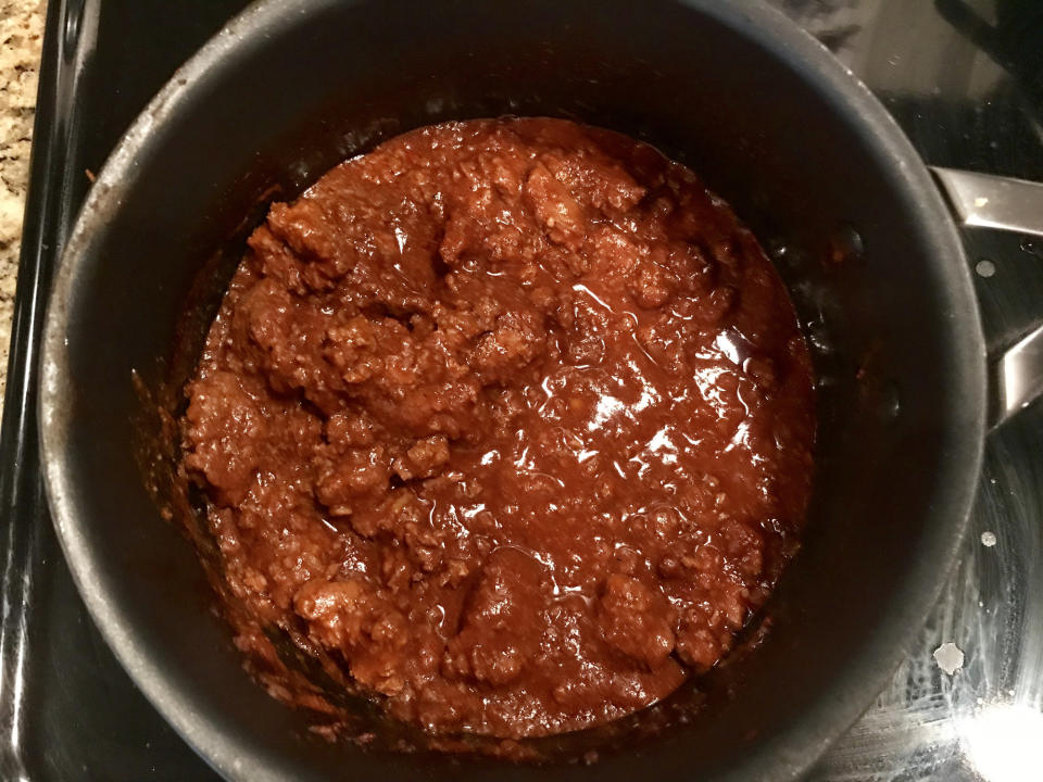 A pot containing a thick, meat-based sauce on a stovetop