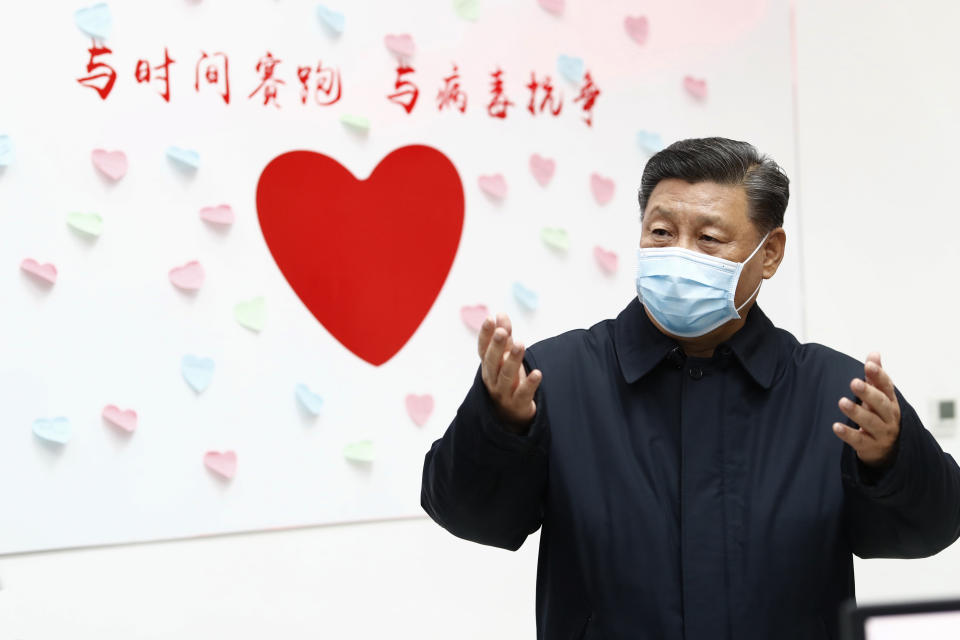 Xi Jinping gestures near a heart shape sign and the slogan "Race against time, Fight the Virus". Source: AP