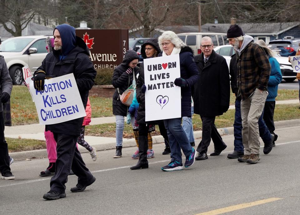 People carry signs reading "abortion kills children" and "unborn lives matter" while participating in Right to Life of Lenawee County's March for Life Monday, Jan. 16, 2023. One of the march participants, U.S. Rep. Tim Walberg, R-Tipton, is pictured fourth from right.