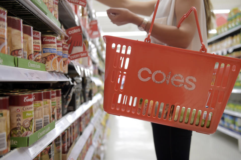 A customer seen in the aisle of the supermarket with a Coles shopping basket.