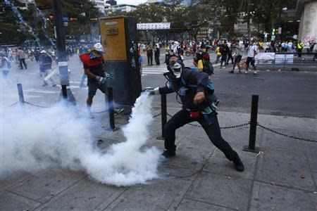 An anti-government demonstrator throws a teargas canister after it was thrown at protesters by the police, during clashes at Altamira square in Caracas February 27, 2014. REUTERS/Tomas Bravo