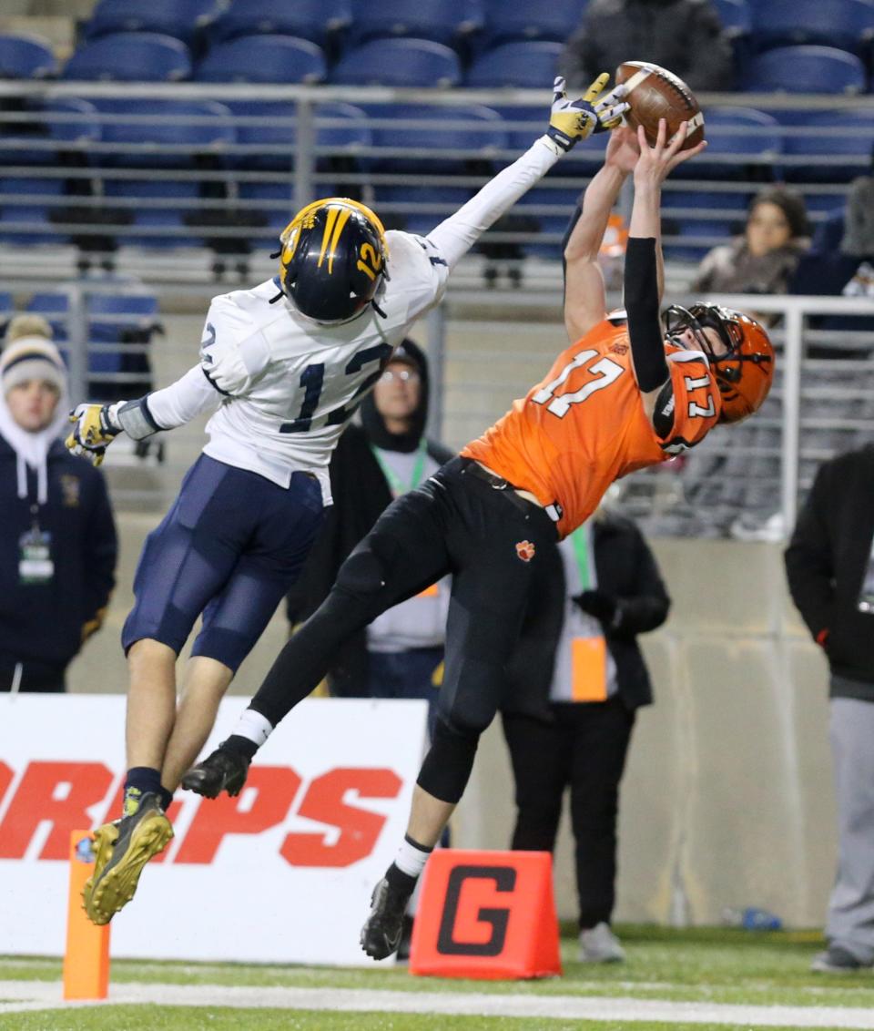 Michael Osborne, 17, of Versailles hauls in a touchdown pass while being defended by Will Sayle, 12, of Kirtland  during their DV state championship game at Tom Benson Hall of Fame Stadium on Saturday, Dec. 4, 2021.