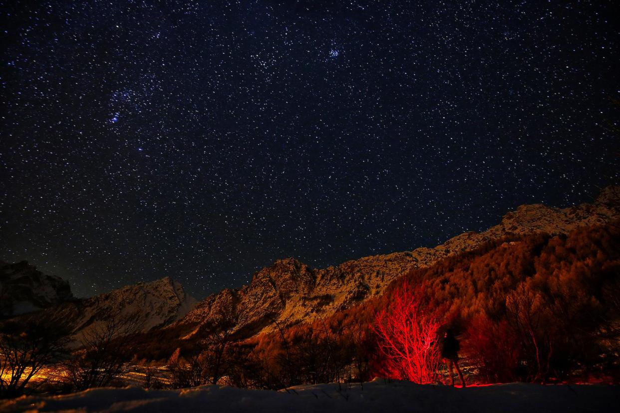 A photographer looks at the sky at night to see the annual Geminid meteor shower near Provenzales' rock, in Maira Valley, northern Italy on December 6, 2016: AFP