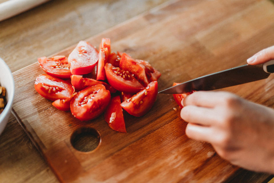 A person cutting tomatoes in the kitchen