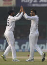 India's bowler Axar Patel, right, celebrates the dismissal of New Zealand's Tim Southee with his teammate Cheteshwar Pujara during the day three of their first test cricket match in Kanpur, India, Saturday, Nov. 27, 2021. (AP Photo/Altaf Qadri)