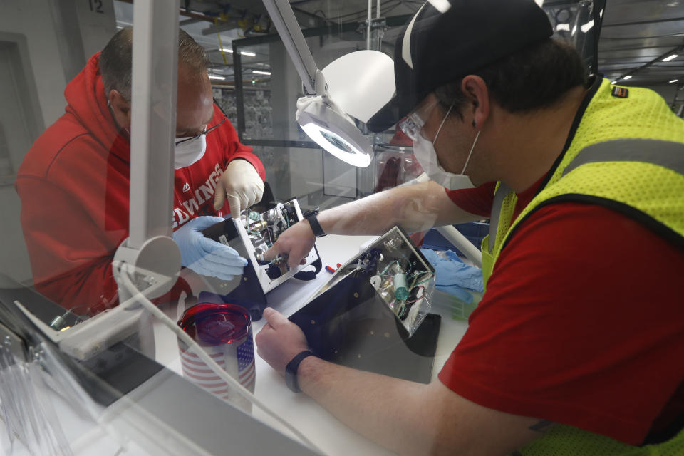 Ford Motor Co., team leader Kyle Lenart, right, inspects a ventilator that the automaker is assembling at the Ford Rawsonville plant, Wednesday, May 13, 2020 in Ypsilanti Township, Mich. The plant was converted into a ventilator factory, as hospitals battling the coronavirus report shortages of the life-saving devices. The company has promised to deliver 50,000 by July 4. Lenart is volunteering to make ventilators at the plant outside Detroit that, beginning Monday, will phase back into producing automotive components. (AP Photo/Carlos Osorio)