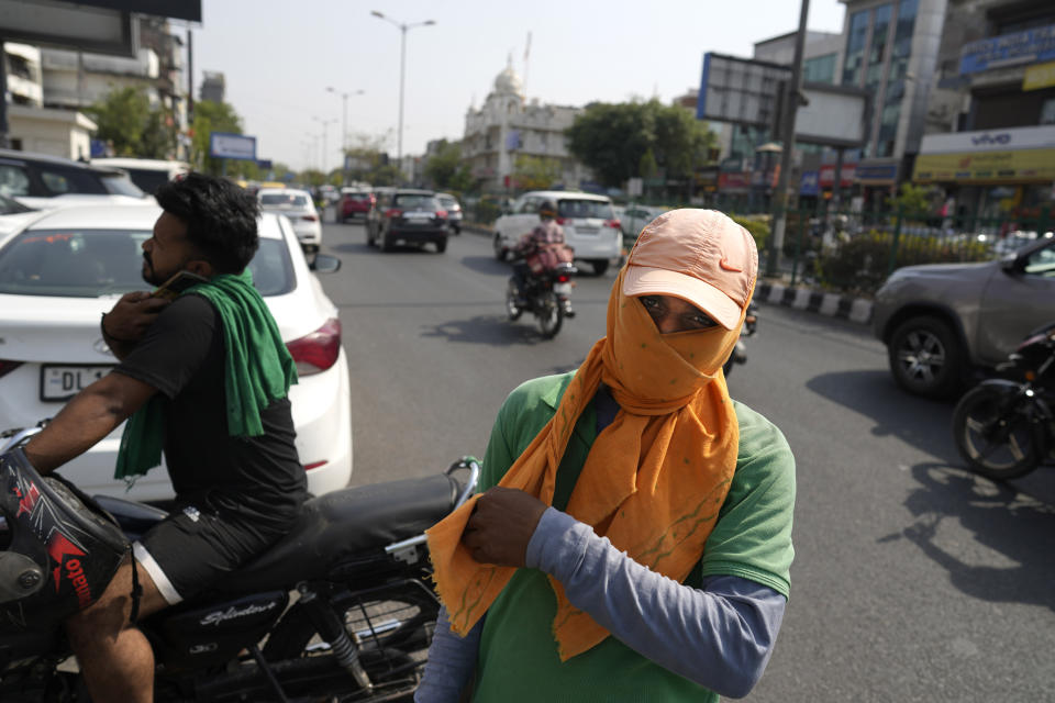 Una persona que ayuda a estacionar autos se cubre el rostro con un pañuelo para protegerse del intenso calor, en Nueva Delhi, India, el 27 de mayo de 2024. (AP Foto/Manish Swarup)