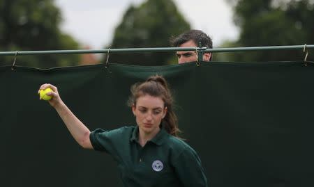 A spectator looks over a barrier to watch the singles match between Portugal's Michelle Larcher De Brito and Belgium's Ysaline Bonaventure during the Wimbledon Tennis Championships qualifying rounds at the Bank of England Sports Centre in Roehampton, southwest London, Britain June 23, 2015. REUTERS/Suzanne Plunkett