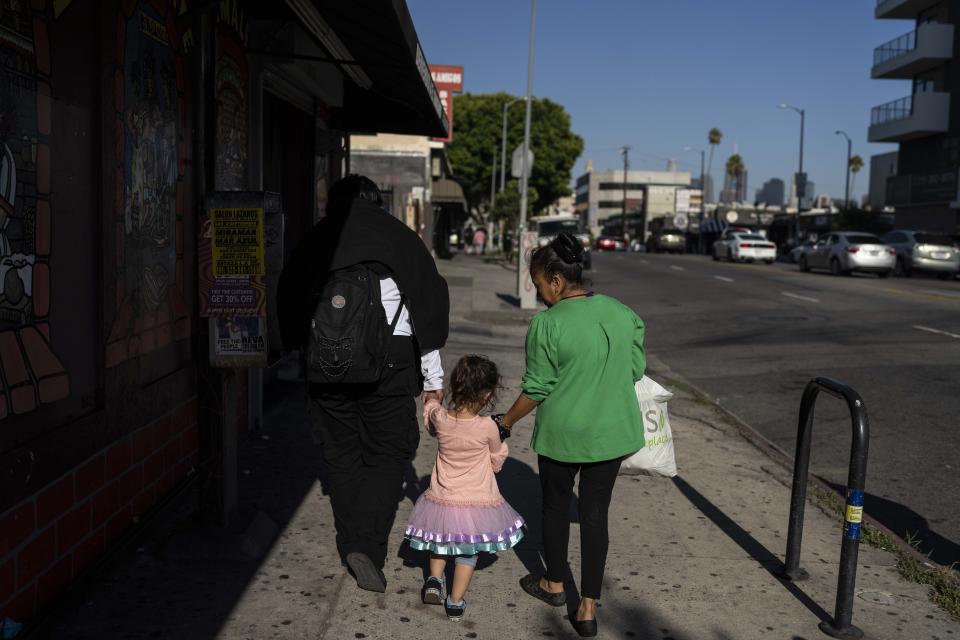 Deneffy Sánchez and his little sister, Jennifer, hold hands as they cross the street to get cold drinks in Los Angeles, Tuesday, Aug. 29, 2023. Jennifer calls her big brother Papa. In one study, more than a third of students who've dropped out since the pandemic said family and adult responsibilities made them leave school. (AP Photo/Jae C. Hong)