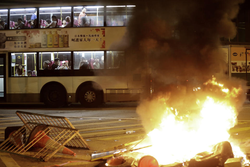 A double decker bus drives past burning debris during clashes between riot police and protesters in Hong Kong, Saturday, Nov. 2, 2019. Riot police fired multiple rounds of tear gas and used water cannons Saturday to swiftly break up a rally in downtown Hong Kong by thousands of masked protesters demanding meaningful autonomy after Beijing indicated it could tighten its grip on the Chinese territory. (AP Photo/Dita Alangkara)