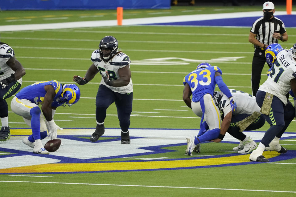 Seattle Seahawks quarterback Russell Wilson, right, fumbles the ball as he is tackled by Los Angeles Rams safety Nick Scott during the second half of an NFL football game Sunday, Nov. 15, 2020, in Inglewood, Calif. The Rams' Leonard Floyd, at left, recovered the ball after the fumble. (AP Photo/Ashley Landis)