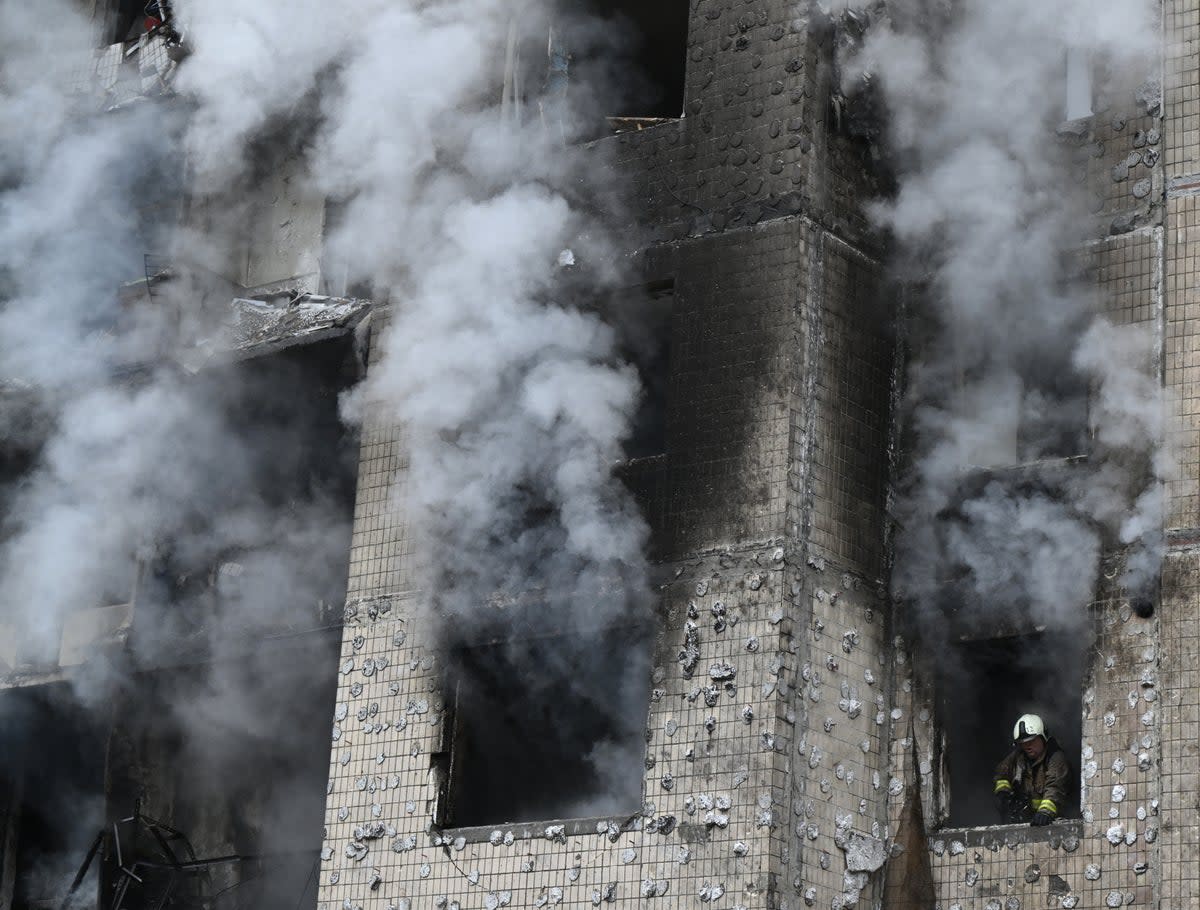 A firefighter looks out of a window as he works in a residential building destroyed by a missile attack in central Kyiv (AFP via Getty Images)