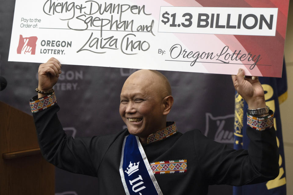 Cheng "Charlie" Saephan holds a check above his head after speaking during a news conference where it was revealed that he was one of the winners of the $1.3 billion Powerball jackpot at the Oregon Lottery headquarters on Monday, April 29, 2024, in Salem, Ore. (AP Photo/Jenny Kane)