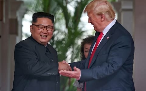 North Korean leader Kim Jong-un and Donald Trump share a joke as they shake hands during their historic summit - Credit: Getty