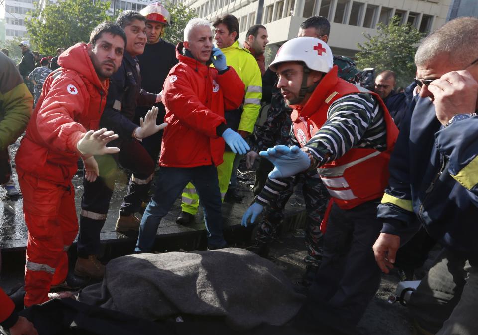 Lebanese Red Cross personnel stand next to a covered body believed to be that of former finance minister Mohamad Chatah after an explosion in Beirut's downtown area December 27, 2013. Shattah, who opposed Syrian President Bashar al-Assad, was killed in an explosion that targeted his convoy in Beirut on Friday along with at least four other people, security sources said. (REUTERS/Jamal Saidi)