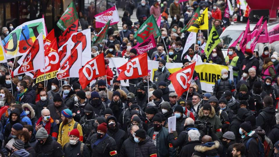 Protestors hold trade unions flags during an interprofessional mobilisation on wages and employment in Paris on January 27, 2022. (Photo by Thomas SAMSON / AFP)