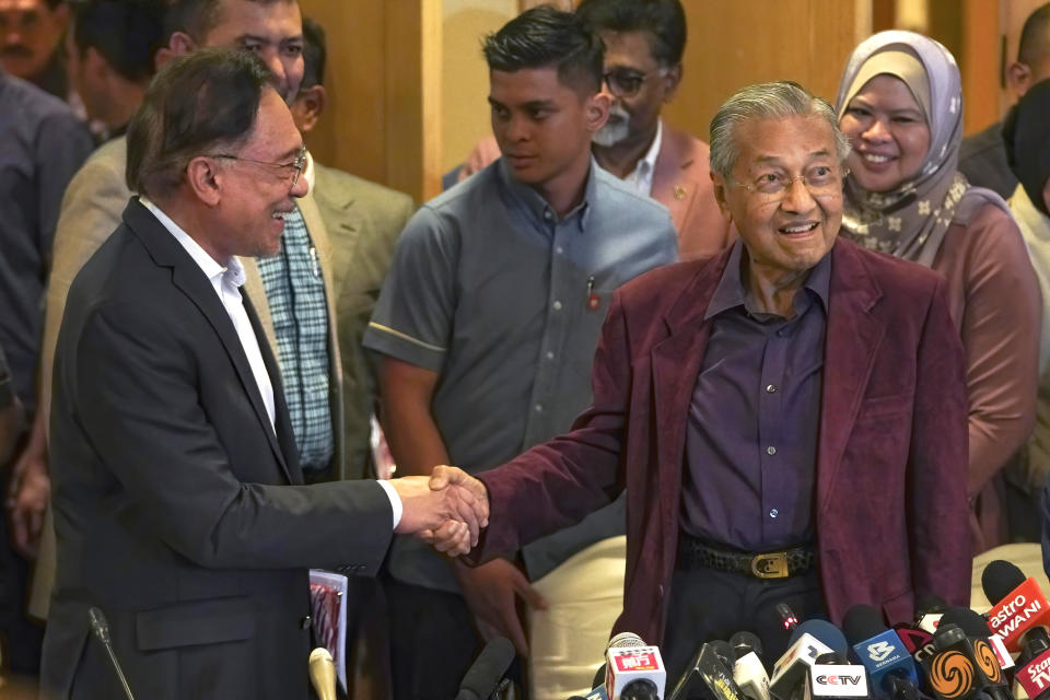 In this Feb. 22, 2020, photo, Malaysian Prime Minister Mahathir Mohamad shakes hand with successor Anwar Ibrahim in Putrajaya, Malaysia. Political tension is building in Malaysia amid talks that Mahathir will pull his party out of the ruling alliance and team up with opposition parties to form a new government in a major political upheaval. It will thwart his named successor Anwar Ibrahim from taking over.(AP Photo/Vincent Thian)