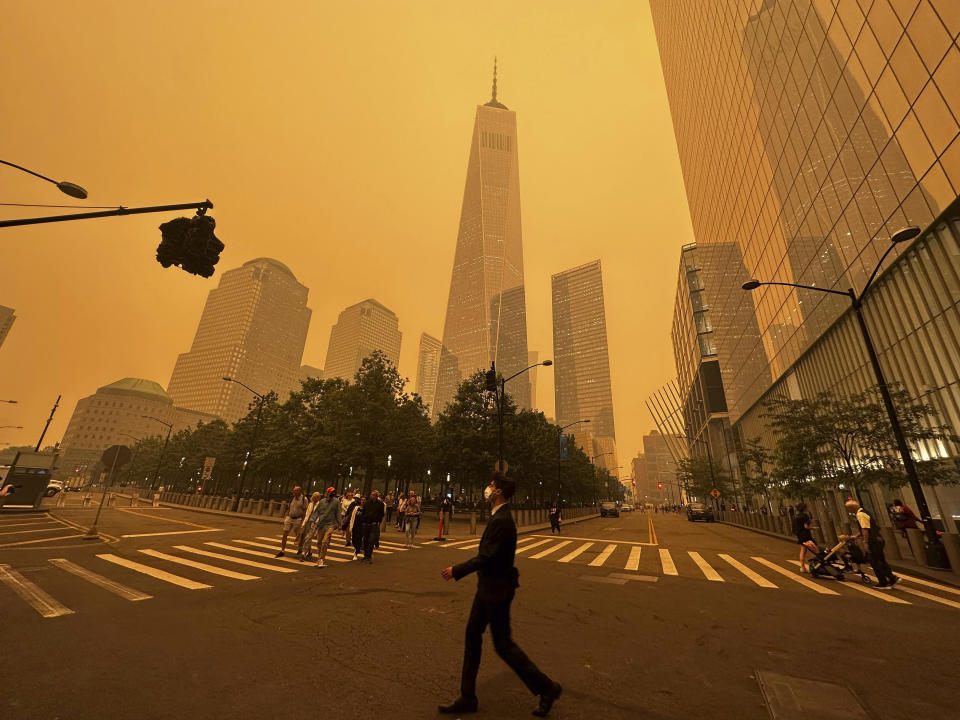 Pedestrians pass the One World Trade Center, center, amidst a smokey haze from wildfires in Canada, Wednesday, June 7, 2023, in New York. (AP Photo/Julie Jacobson)